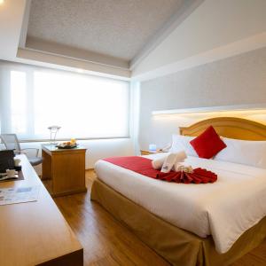 莫雷利亚Hotel Horizon & Convention Center的一间卧室配有一张带红色枕头的大床