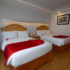 莫雷利亚Hotel Horizon & Convention Center的酒店客房,配有两张带红色床单的床