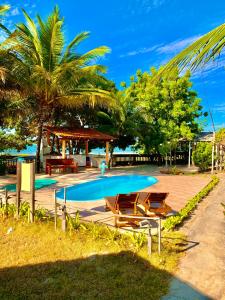 日若卡-迪热里科阿科阿拉Pousada Sol Dourado的一个带桌椅的游泳池,以及棕榈树