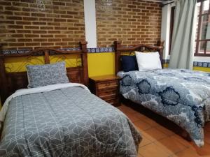 奇格纳瓦潘Hotel Y Suites Axolotl的一间卧室设有两张床和砖墙