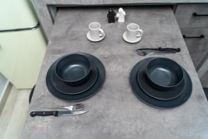 沃洛斯Salina Premium Residences Volos的一张桌子,上面有黑盘和杯子,餐具