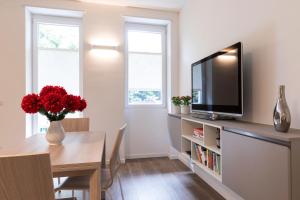 米兰West Milan - Modern and Comfortable Apartment的客厅配有电视和红色鲜花桌