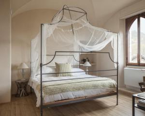 加比亚诺盖比亚诺城堡酒店的卧室配有带白色床单的天蓬床