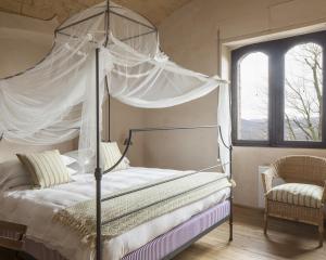 加比亚诺盖比亚诺城堡酒店的一间卧室设有天蓬床和窗户。