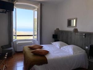 Rogliano尤桑塔涅鲁酒店的一间卧室设有一张大床和大窗户