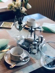 韦茨拉尔Hotel Altstadt Wöllbacher Tor的桌子,桌子上放有盘子和杯子,花瓶