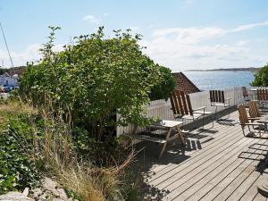 Hälleviksstrand6 person holiday home in H LLEVIKSSTRAND的一个带椅子的木甲板和水边的灌木