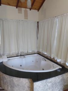 蒙特韦尔迪Chalés Recanto Vista do Valle的配有窗帘的客房内的大浴缸