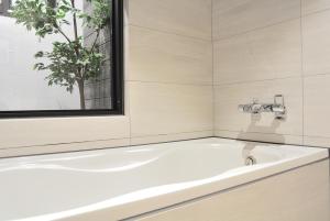 台中市逢甲K行旅（久窝旅店）的带窗户的浴室内的白色浴缸