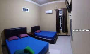 巨港Rian Kost - Hotel Penginapan Murah Pusat Kota Palembang的配有蓝色床单和紫色枕头的客房内的两张床