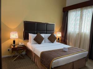 阿布扎比Downtown Plaza Hotel Apartment Pet Friendly的酒店客房设有一张大床和两盏灯。