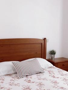 圣佩罗德姆Casa dos Pinheiros的一张带木制床头板和条纹枕头的床