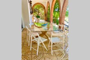 奇克拉纳－德拉弗龙特拉Agradable casa de campo con piscina en la Barrosa的庭院内一张带白色椅子的玻璃桌