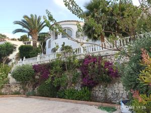 卡尔佩Villa med panoramautsikt med privat pool i Calpe, Costa Blanca, Spanien的白色的房子,有白色的围栏和紫色的鲜花