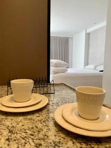 若昂佩索阿Manaíra Apart Hotel的卧室的柜台上有两个杯子和盘子