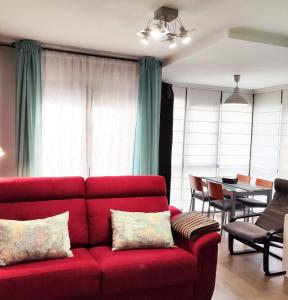 塞哥维亚El Balconcito de San Millan的客厅里一张红色的沙发,配有桌子