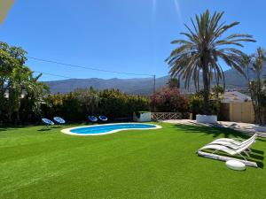 ArafoArafo Sunset Villa的一个带椅子的庭院和一个带草地的游泳池