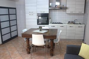 PortacomaroCasa Graziella - la casetta的厨房配有木桌和白色椅子