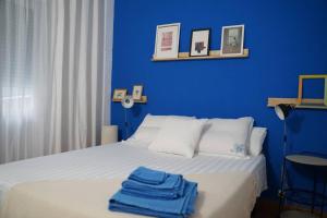萨拉戈萨Apartamento Único en Plaza del Pilar的蓝色卧室,配有带2条毛巾的床