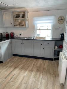 BallintoberDream Cottage的厨房铺有木地板,配有白色橱柜。