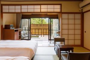 箱根Hakone Kowakien Mikawaya Ryokan的一间卧室设有一张床,并有通往庭院的门