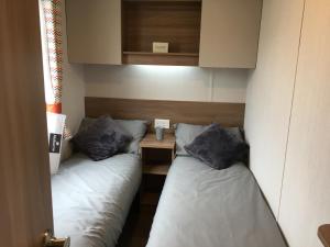 基督城3 Bed Luxury Mobile Home Hoburne Park Christchurch的小型客房配有两张单人床和一张桌子。