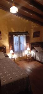 BenadalidCasa rural El Patio的一间卧室设有两张床、两盏灯和一个窗户。