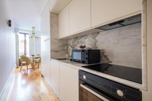 波尔图Douro Golden Studio的厨房配有白色橱柜和黑炉灶烤箱。