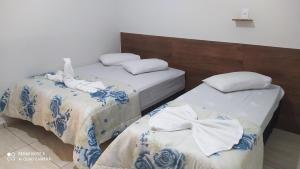 阿帕雷西达Pousada Quarto com tv,ar,frigobar,wifi e garagem的两张位于酒店客房的床,配有毛巾