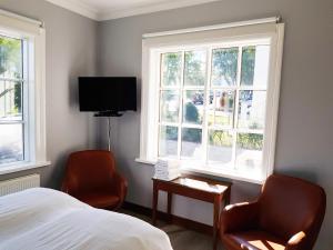 阿克雷里FE Gisting的一间卧室配有两把椅子、一张床和两个窗户。