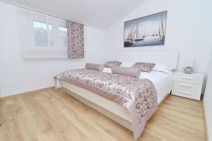 尼亚卢卡Villa Green Bay Apartments的白色的卧室配有一张床,墙上挂着一幅画