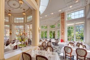 皮耶什佳尼Ensana Thermia Palace的餐厅设有白色的桌椅和窗户。