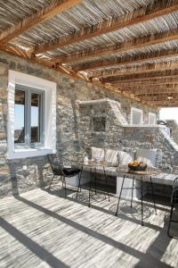 斯希努萨岛Africanis Bungalows的一个带桌椅和石墙的庭院