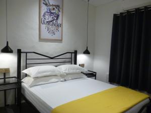 马六甲Ola Hostel的卧室配有一张白色大床和黄色毯子