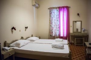 阿尔戈斯托利翁阿尔戈斯托利酒店的一间卧室设有两张床,窗户配有粉红色的窗帘