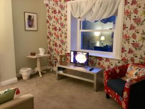 MaugholdThe Glen Mona Hotel的客厅设有一张桌子和一扇窗户,配有电视。