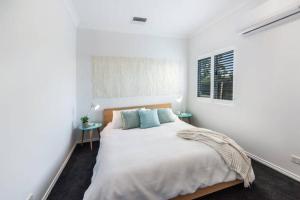 莫阿马Malibu Palms - Echuca Holiday Homes的一间白色卧室,配有一张大床和两张桌子