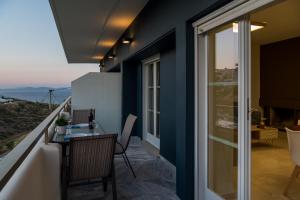 拉斐那CHROMA Lodge Rafina的阳台设有玻璃桌,享有海景。