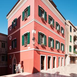 希贝尼克King Kresimir Heritage Hotel的街道上一座红色的建筑,设有绿色百叶窗