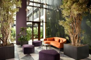 米兰Milano Verticale | UNA Esperienze的一个带橙色沙发和紫色凳子的办公室大堂