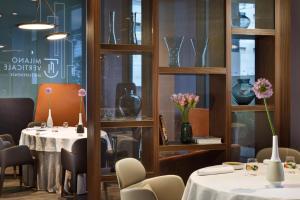 米兰Milano Verticale | UNA Esperienze的一间在架子上摆放着桌椅和花瓶的餐厅