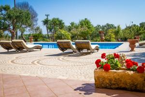 莱乌卡Villa Vanessa的圆形休息区,配有椅子和鲜花,毗邻游泳池