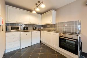 阿普比2 Mews Cottages - Town Centre Location的厨房配有白色橱柜和炉灶烤箱。