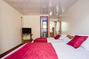 波哥大Touristic House的一间卧室配有两张带红色枕头的床和电视。