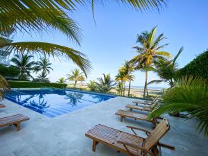 卡塔赫纳Apartamento en Cartagena con vista al mar的一个带椅子和棕榈树的游泳池以及大海