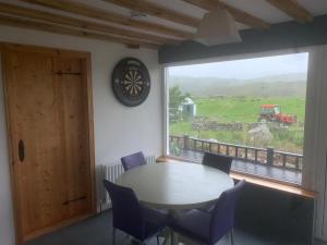 DoocharyBeautiful Thatched Adderwal Cottage Donegal的配有大窗户的客房内的桌椅