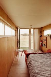 EssenSlapen tussen de paarden的一间卧室配有一张床、一张桌子和一个窗户。