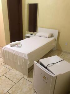 Nova Santa MedianeiraHotel Dom Alcides的卧室配有白色的床和冰箱。