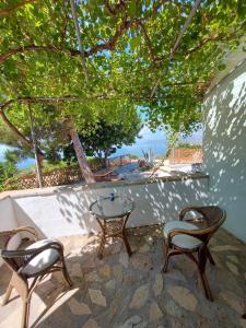 KoumeikaBeautiful house located on a hill in Samos Island, 400 m from an organized beach的庭院配有两把椅子、一张桌子和一张桌子