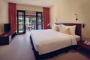 沙努尔萨努尔美居度假酒店的卧室配有一张白色大床和电视。
